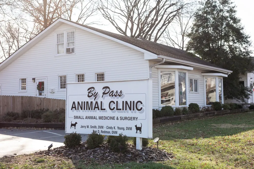 Exterior of By Pass Animal Clinic, a white-sided building with a large sign listing veterinary services and doctors' names.